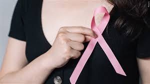 Image of a woman holding a pink ribbon over her breast. 