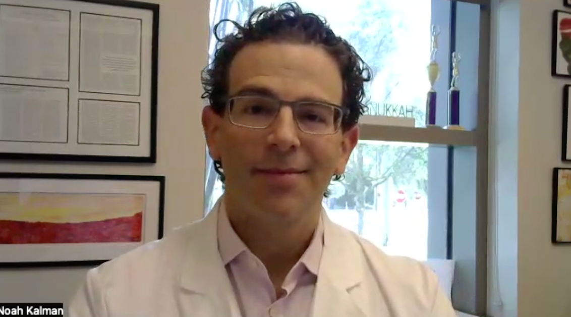 Image of a doctor with dark curly hair and rectangular glasses.