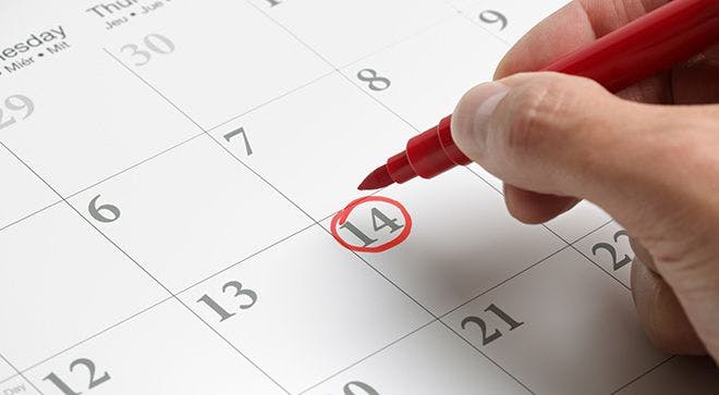 person using a red pen to circle a date on a calendar