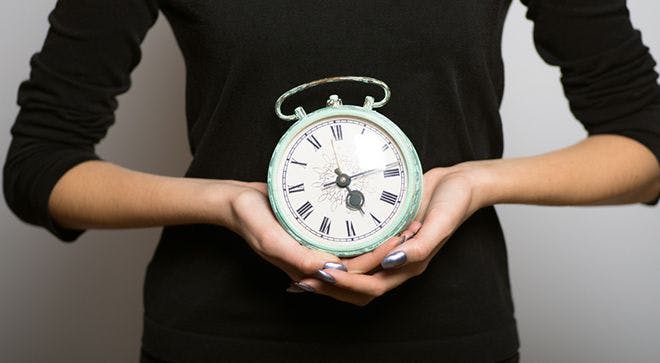 Image of a person holding an analog clock.