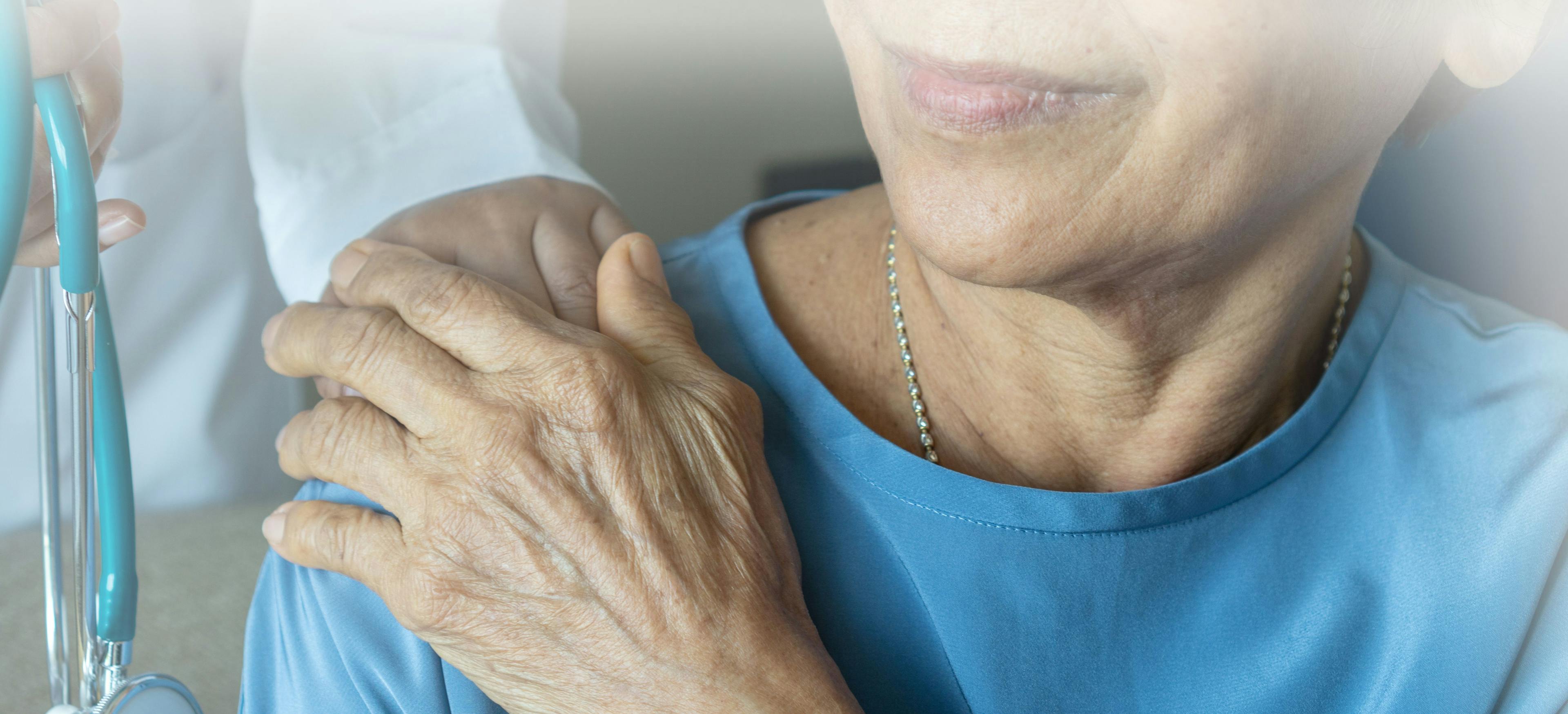 elderly woman holding the hand of an oncology nurse