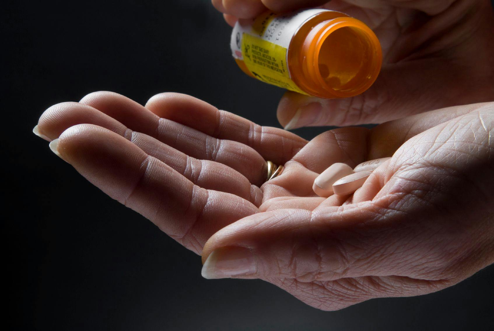 Image of a person pouring pills into their hands. 