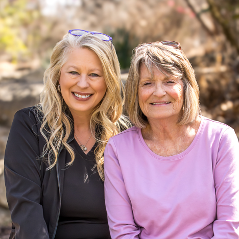 Image of two women sitting on a bench outside.