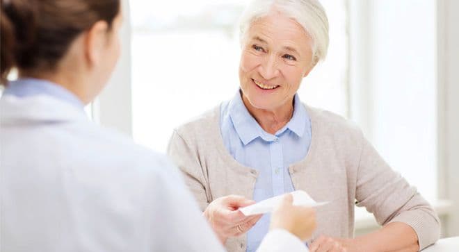 Image of a doctor speaking with a patient with white hair in a bun. 