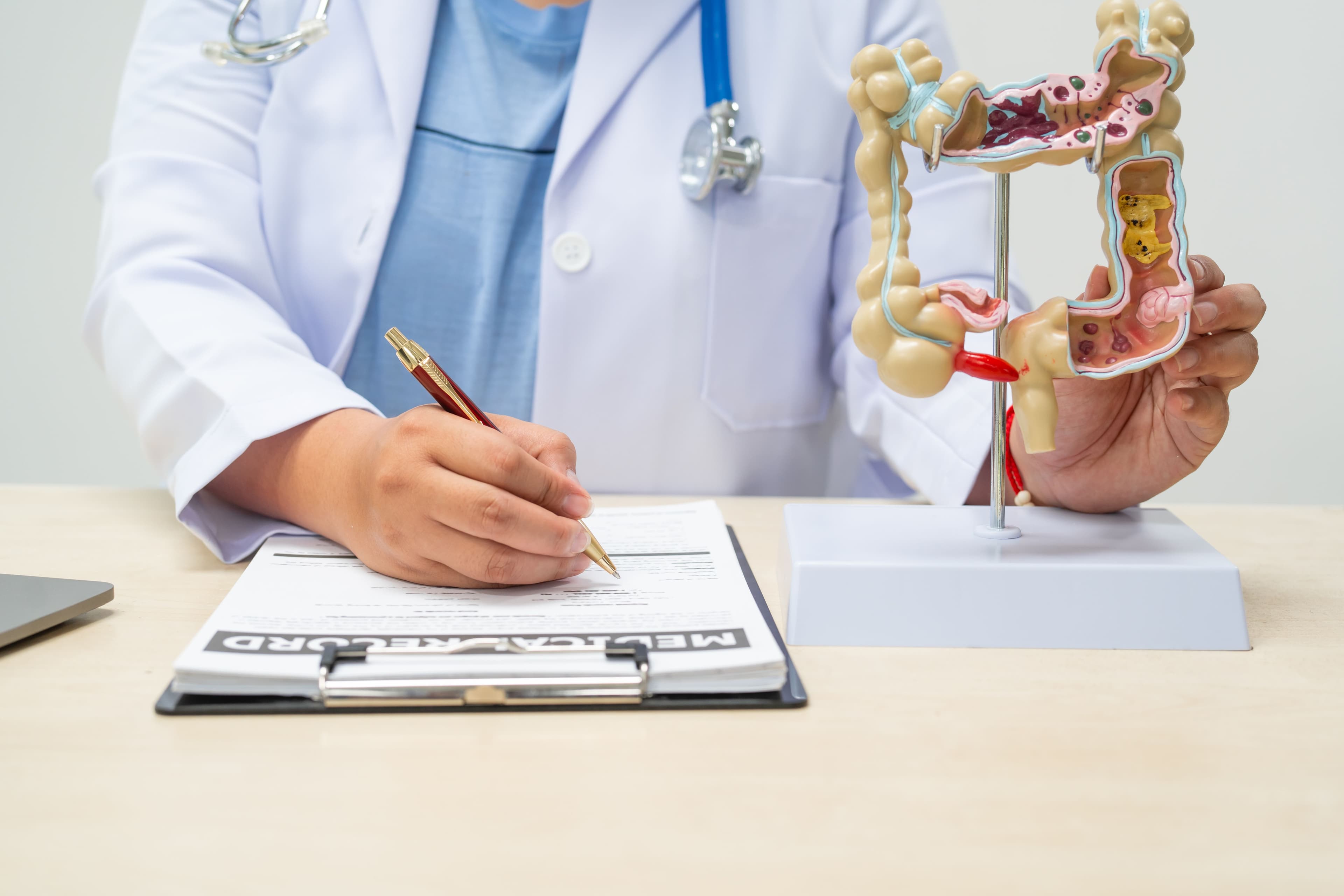 A female doctor sits at a table in a hospital, discussing intestinal health issues, including appendicitis, colon cancer symptoms, diarrhea,constipation, blood in stool, unexplained weight loss.