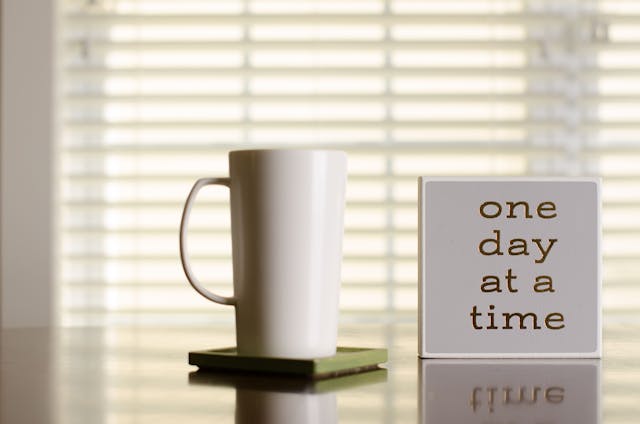 Image of a mug next to a sign that says "One day at a time."