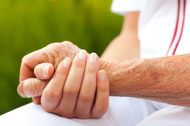 Image of a nurse holding a patient's hand. 