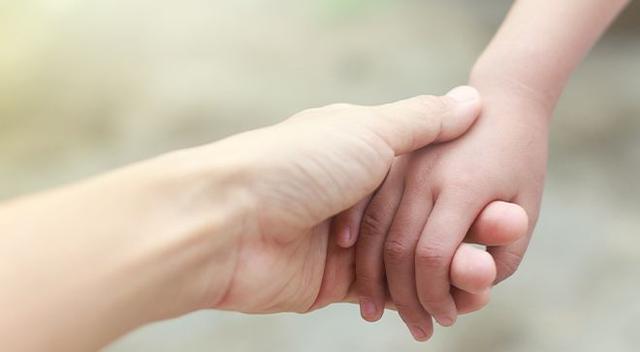 Image of a adult holding a child's hand. 