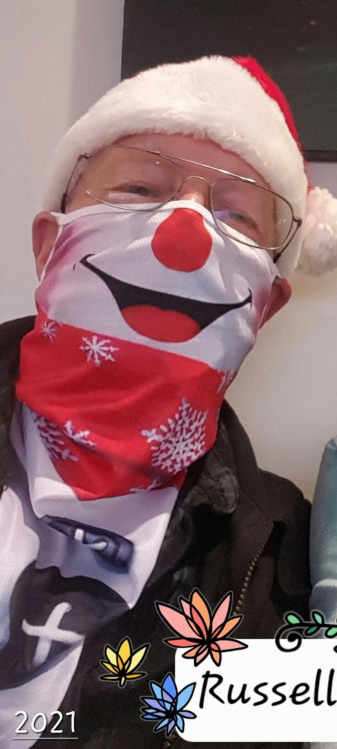 Image of a man wearing a Santa hat and a snowman face mask. 