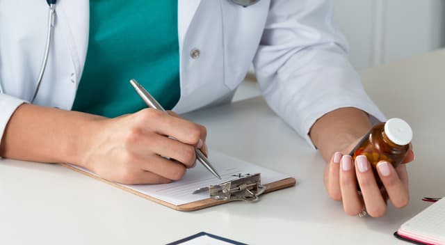 Image of a doctor holding a bottle of pills.