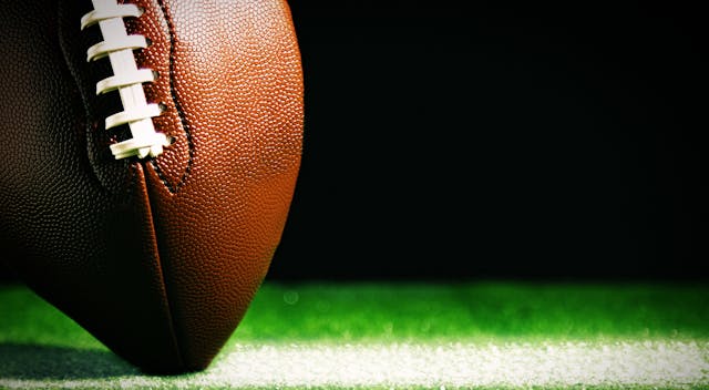 Image of a football up close, touching the turf below it. 